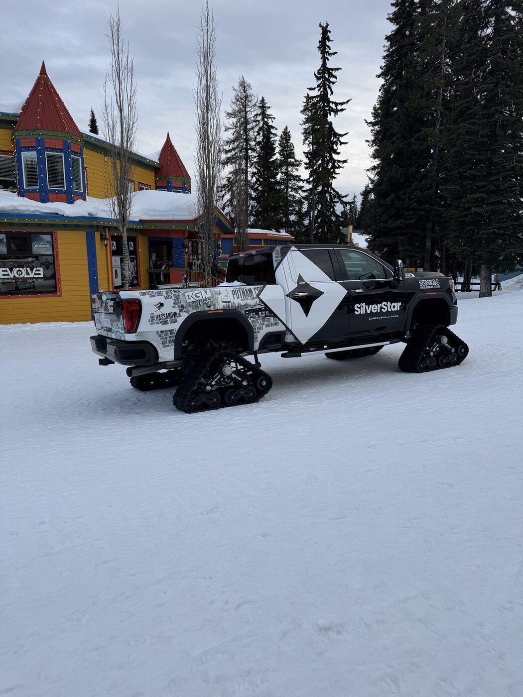 A SilverStar-branded snow groomer parked outside the colourful village buildings