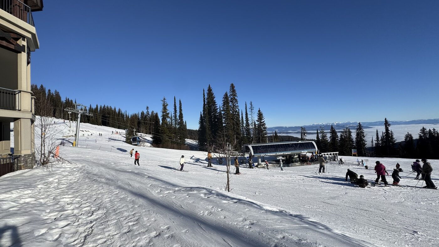 Skiers on the slopes at SilverStar with the chairlift and village in the background under blue sky