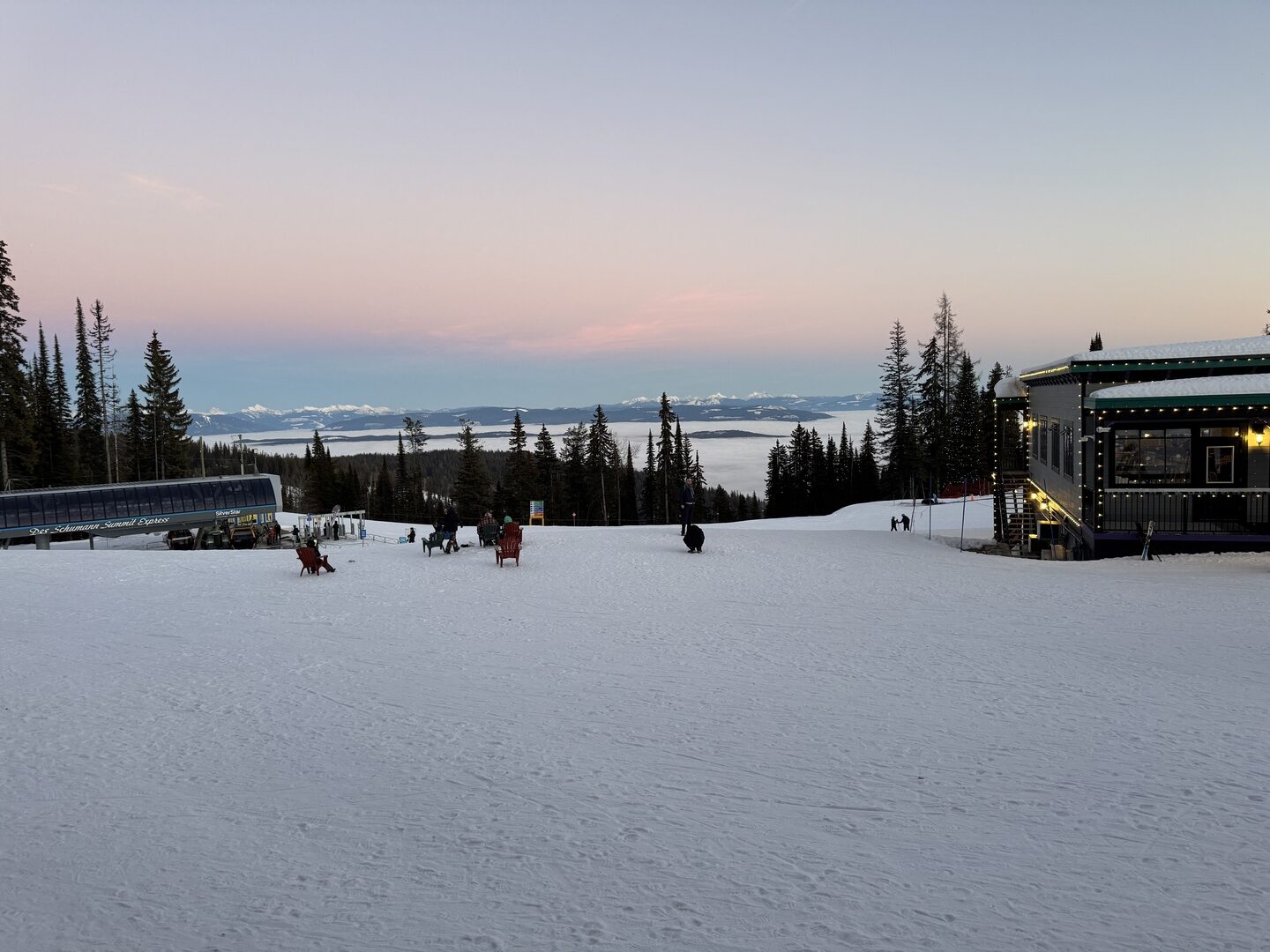The Sky Chairsome Summit Express chairlift and mountain lodge at SilverStar Ski Resort at dusk, with a sea of cloud filling the valley below